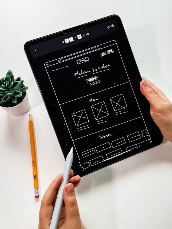 Website wireframe on a iPad with a apple pencil in hand.