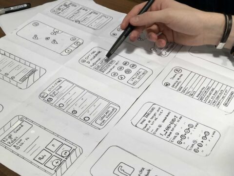 UX/UI concept designs on multiple sheets of paper